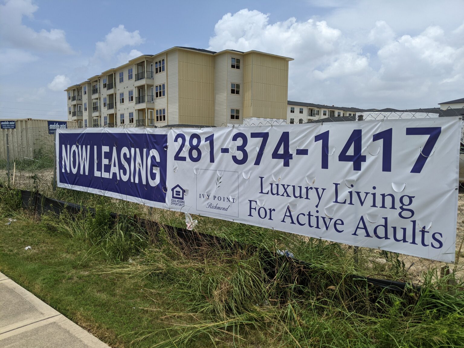 Now Leasing banner on fencing outside an apartment development — Intrepid Signs, Rosenberg TX
