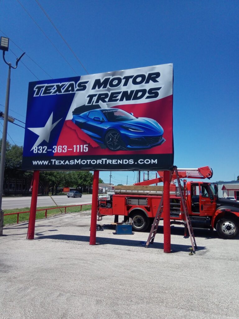 Texas Motor Trends billboard above a car lot